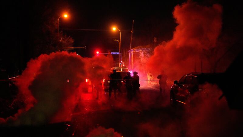 Agentes federales rodeados de gas lacrimógeno salen del sitio de un tiroteo, el miércoles 14...