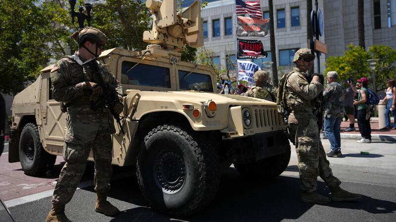 Soldados de la Guardia Nacional de California vigilan una calle cerca de manifestantes y...
