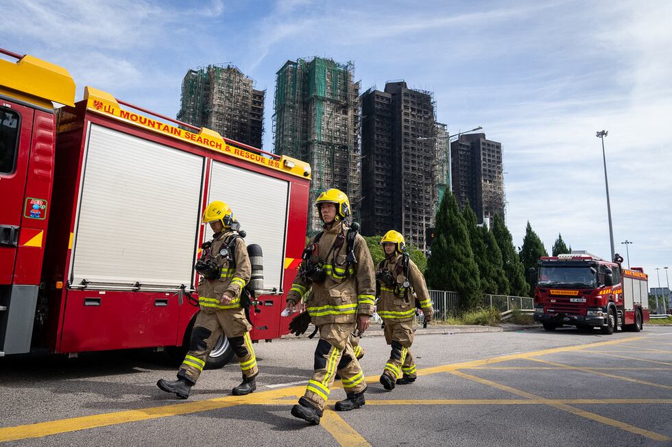 Bomberos pasan por delante de las torres que se incendiaron en el complejo habitacional Wang...
